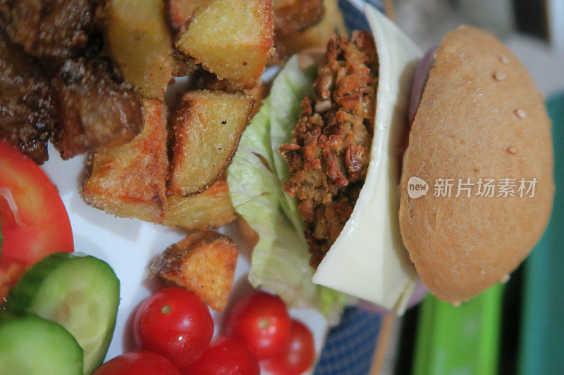 这是一个自制的素食汉堡/豆汉堡食谱，里面有捣碎的菜豆和洋葱，有芝麻的面包，融化的加工过的奶酪片，生菜，樱桃番茄和炸土豆条/薯条丁，薯条丁和沙拉